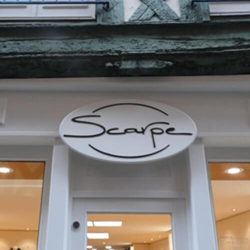Enseigne métal ronde « Scarpe » au-dessus d'une entrée
